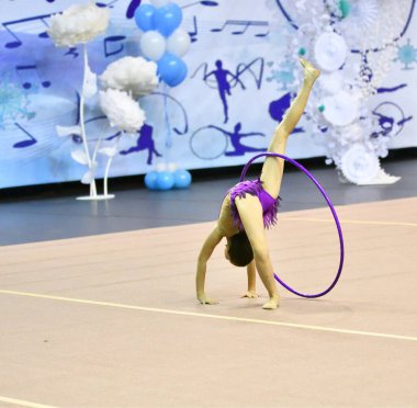 Kız, ritmik jimnastikte zorunlu bir program yürütüyor. 