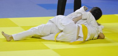 Kimonolu iki kız judoka tatamide yarışıyor. 