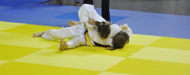 Kimonolu iki kız judoka tatamide yarışıyor. 