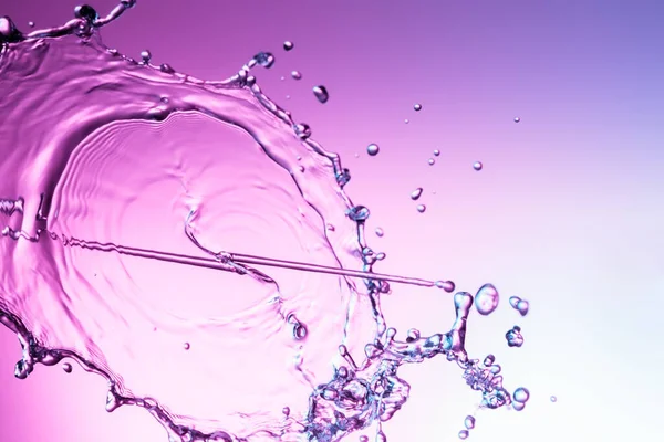 Klares Wasser Flüssigkeit Spritzer Auf Einem Lila Hintergrund lizenzfreie Stockfotos