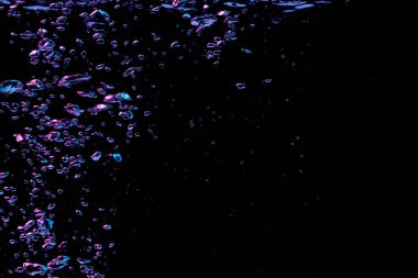 Kırmızı ve mavi ışıkta şeffaf berrak su içinde bir kabarcık sıçrıyor siyah doğa arka planında