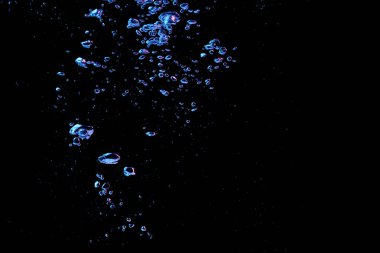 Kırmızı ve mavi ışıkta şeffaf berrak su içinde bir kabarcık sıçrıyor siyah doğa arka planında