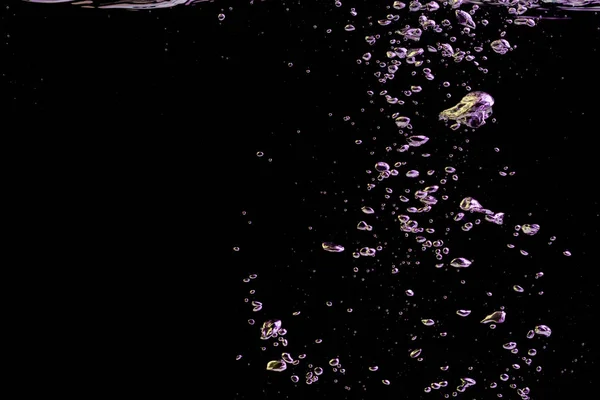黒い自然を背景に黄色と紫の光の中で透明な水の液体中のバブルスプラッシュ — ストック写真
