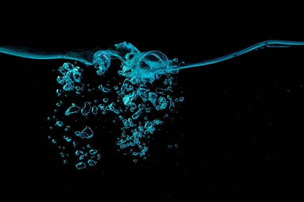 黒い自然を背景に 青い光の中に波紋と泡を持つ透明な水面 — ストック写真