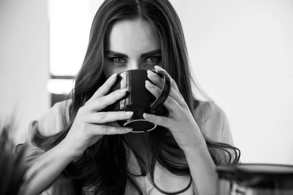 Seductive Girl Drinks Tea and Looks Intriguingly into the Camera. Black and White photo Stock Obrázky