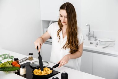 Kız tavada omlet pişiriyor. 