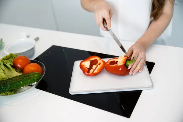 A young woman make a salad with vegetables. Immagine Stock