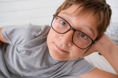 Tembel, neşeli, gözlüklü, yatakta yatıp dinlenen bir çocuk. Çünkü ne okulda ne de karantinada..