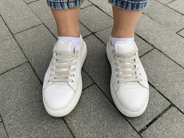 白い革のレースのスニーカーを屋外で身に着けている女性の足 都会の生活のためのトレンディーな靴 公園を歩く — ストック写真