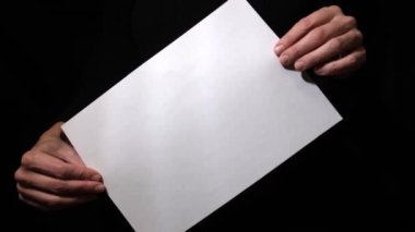 Eller boş beyaz kağıt tutarak siyah zemin üzerinde, döndür ve sabit tut metin, reklam ve giriş için uygun
