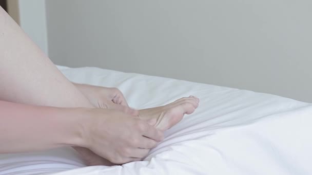 Mulher fazendo massagem nos pés na cama, alívio para pernas e pés cansados, cuidados com o corpo e tratamento em casa — Vídeo de Stock