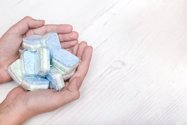 Suda çözünür ambalajlarda birçok yeşil ve mavi bulaşık deterjanı tutan eller, boşluğu kopyala — Stok fotoğraf