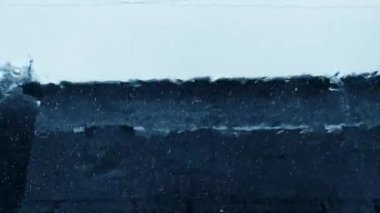 Sağanak yağmur, yağmur damlaları ön cama düşüyor, park halindeki bir arabanın kasvetli manzarası.