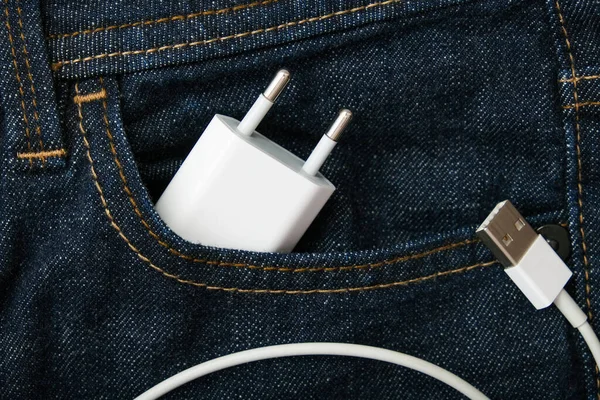 Cargador USB, adaptador de cable para smartphone y gadgets en un bolsillo vaquero tomado en un viaje — Foto de Stock