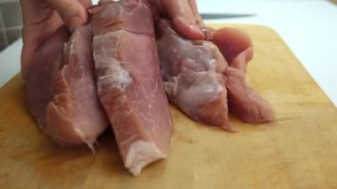 A butcher showing cut sliced pork meat close up, selling fresh organic meat at a market