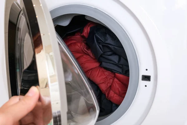 A hand clothing a drum of a washing machine after loading dirty clothes, laundry concept — Fotografia de Stock