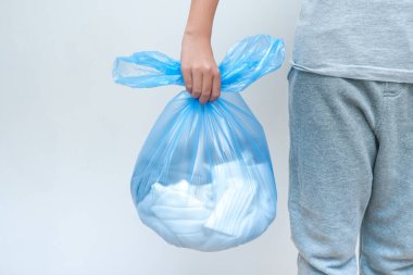 Geri dönüşüm için büyük bir plastik çanta taşıyan bir genç.