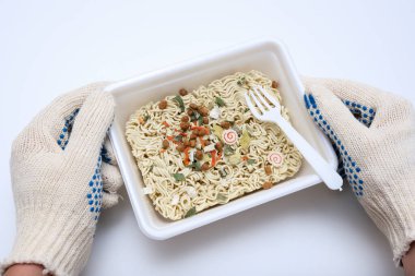 Bir inşaat işçisinin elleri hazır yemek yiyor, Çin eriştesi yiyor, öğle yemeği yiyor..