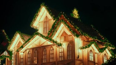 Işıklar parıldayan çelenkler ev manzarası. Noel köyü, ahşap ev manzarası süsü. Yılbaşı ağacı dalları yeni yıl süslemesidir.