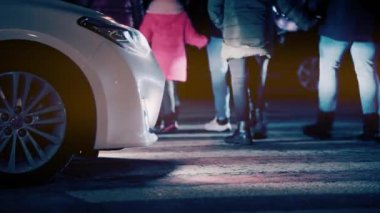 Yaya geçidinde yürüyen kalabalık. Gece şehri iş adamları yolun karşısına taşınıyor. Trafik güvenli hız, farlar