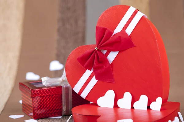 Red box in heart shape next to a gift box — Stock Photo, Image