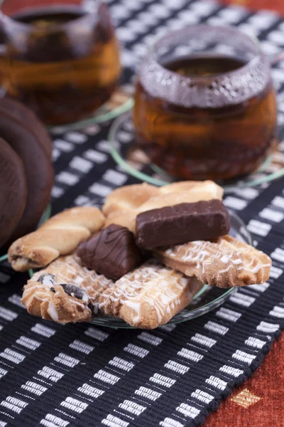 Plate with cookies next to two cup of tea