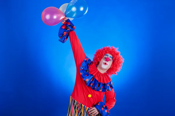 Šťastný klaun s balónkem na modrém pozadí — Stock fotografie