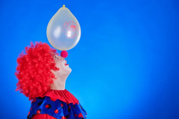 Счастливый клоун с шаром на синем фоне — стоковое фото