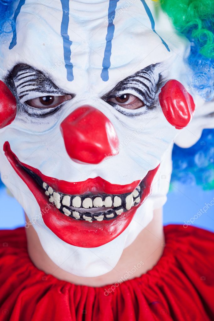 Scary clown person in clown mask on blue background