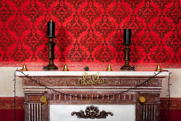 Twee kaarsen in een brand plaats Kerstmis vintage kamer op een rode rug — Stockfoto