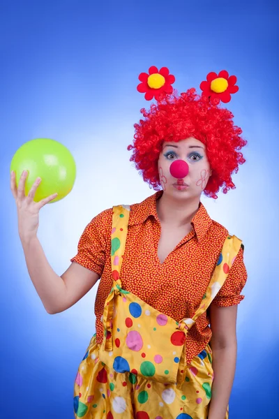 Trauriger Clown mit Ball in der Hand auf blauem Hintergrund — Stockfoto