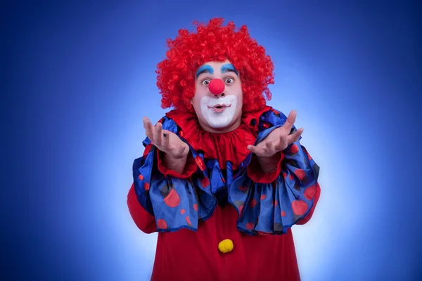 Fröhlicher Clown im roten Kostüm auf blauem Hintergrund — Stockfoto