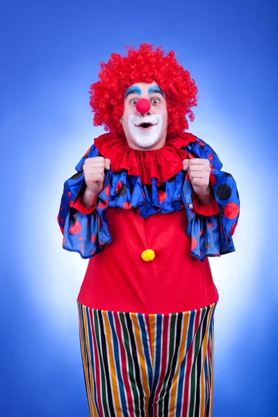 Fröhlicher Clown im roten Kostüm auf blauem Hintergrund — Stockfoto