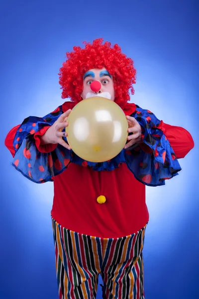 Palhaço com balão em traje vermelho no fundo azul — Fotografia de Stock