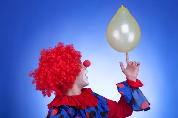 Palhaço de traje vermelho jogando com balão amarelo — Fotografia de Stock