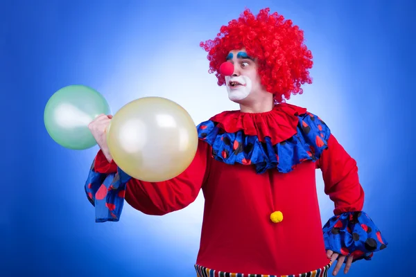 Клоун з повітряними кулями в руці на синьому фоні — стокове фото