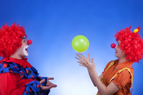 Coppia di clown che gioca con pallone su sfondo blu — Foto Stock