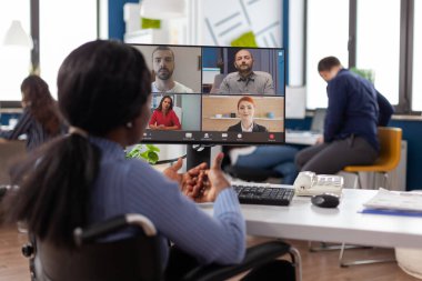 Felç olmuş, tekerlekli sandalyedeki Afrikalı Amerikalı menajer internetten video görüşmesi yapıyor.