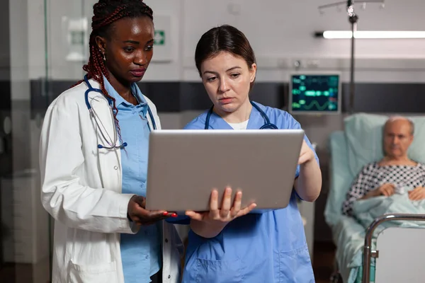 Африканский американский врач и медсестра с помощью ноутбука в больничной палате — стоковое фото