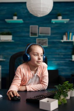 Kulaklıklı küçük okul çocuğu online edebiyat dersi veriyor.