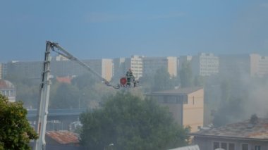 Platformdaki itfaiyeciler evin çatısında yangın çıkarıyorlar.