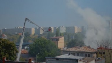 Platformdaki itfaiyeciler yangını söndürmek için çatıya çıkıyorlar.
