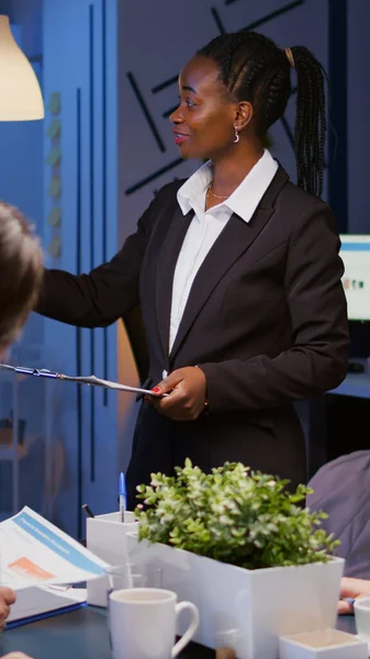 Afrikanischer Workaholic-Führer steht vor Präsentationsmonitor und erklärt Marketingprojekt — Stockfoto