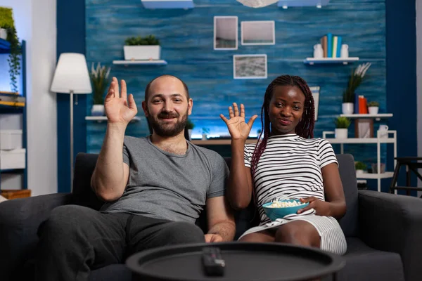 Interracial couple waving at video call camera using technology — Stock Photo, Image