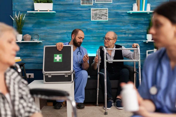 Assistente social discutindo medicamentos de saúde com idosos aposentados com deficiência — Fotografia de Stock