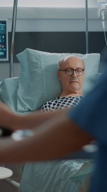 Hemşire, hastanenin koğuşunda hasta bir hastayla konuşuyor.