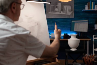 Beyaz tuval üzerine vazo tasarımı çizen Kafkas kıdemli bir adam.