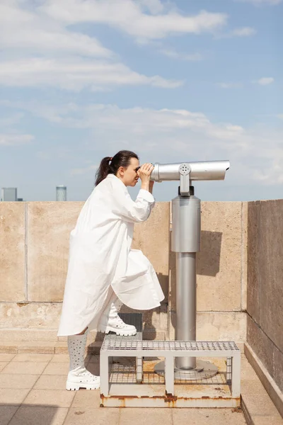 Jeune toursit femme debout sur la tour de construction regardant à travers le télescope jumelles — Photo