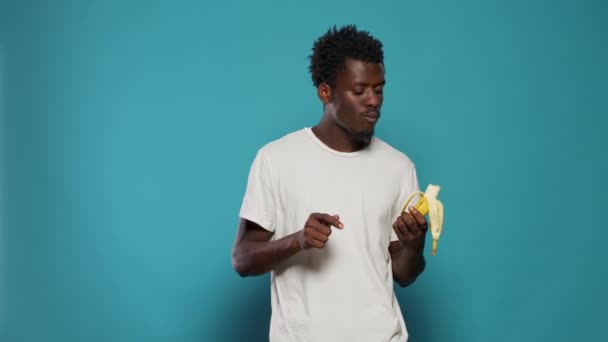スタジオでカメラでバナナを食べるカジュアルな大人の肖像 — ストック動画