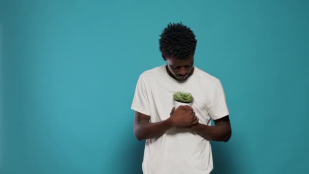 Joven sosteniendo maceta con planta verde — Vídeo de stock